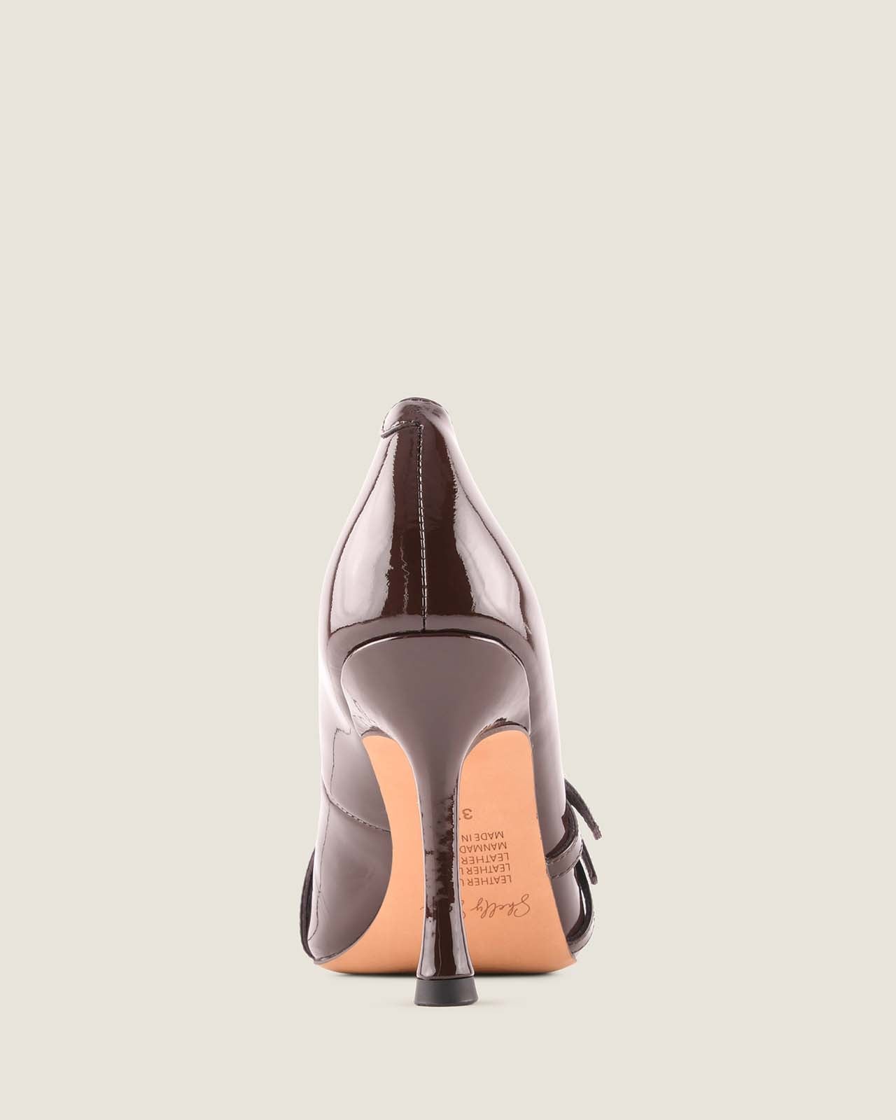 Brown patent leather high-heeled shoe on a light grey background