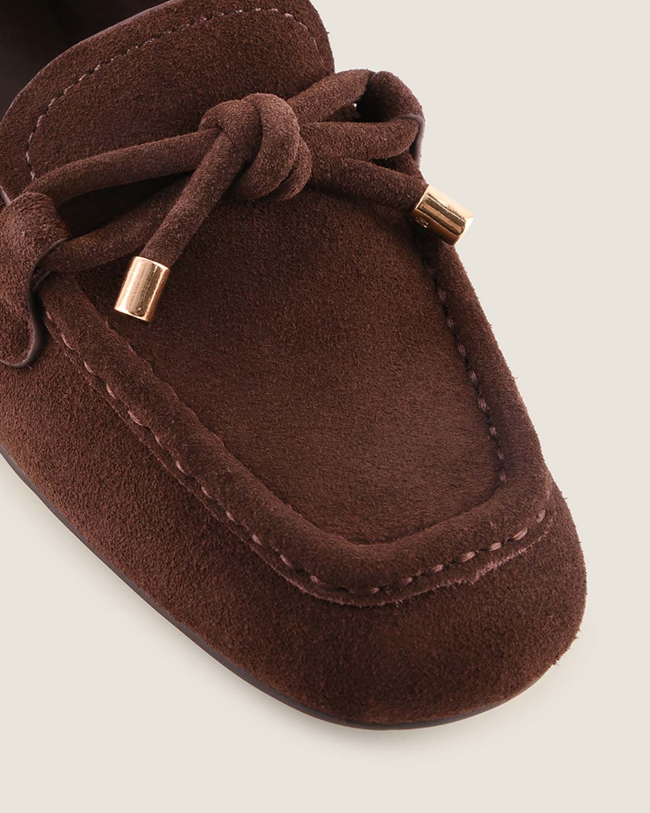 Brown suede loafer shoe with a knot on a light background