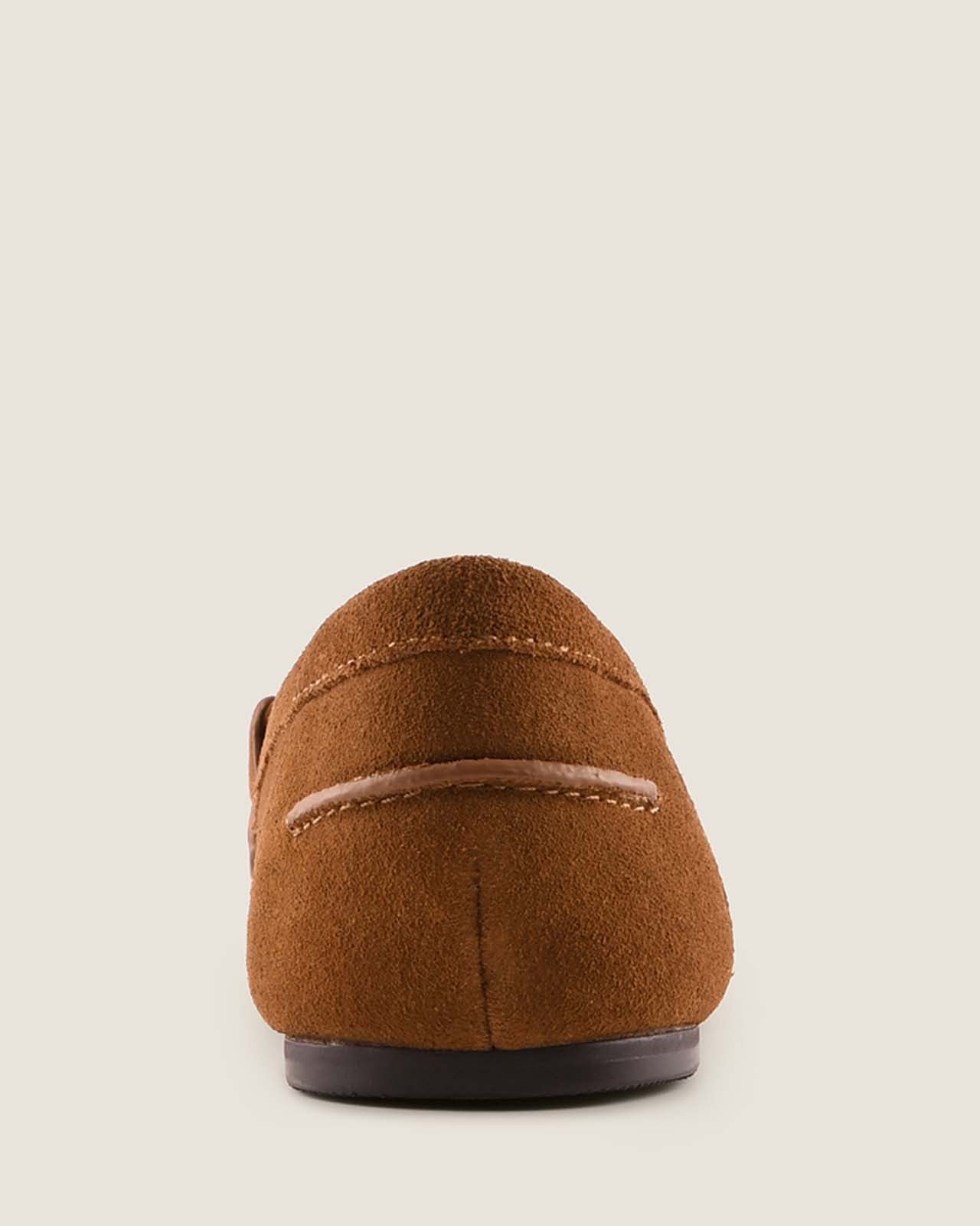 Tan suede loafer on a light beige background