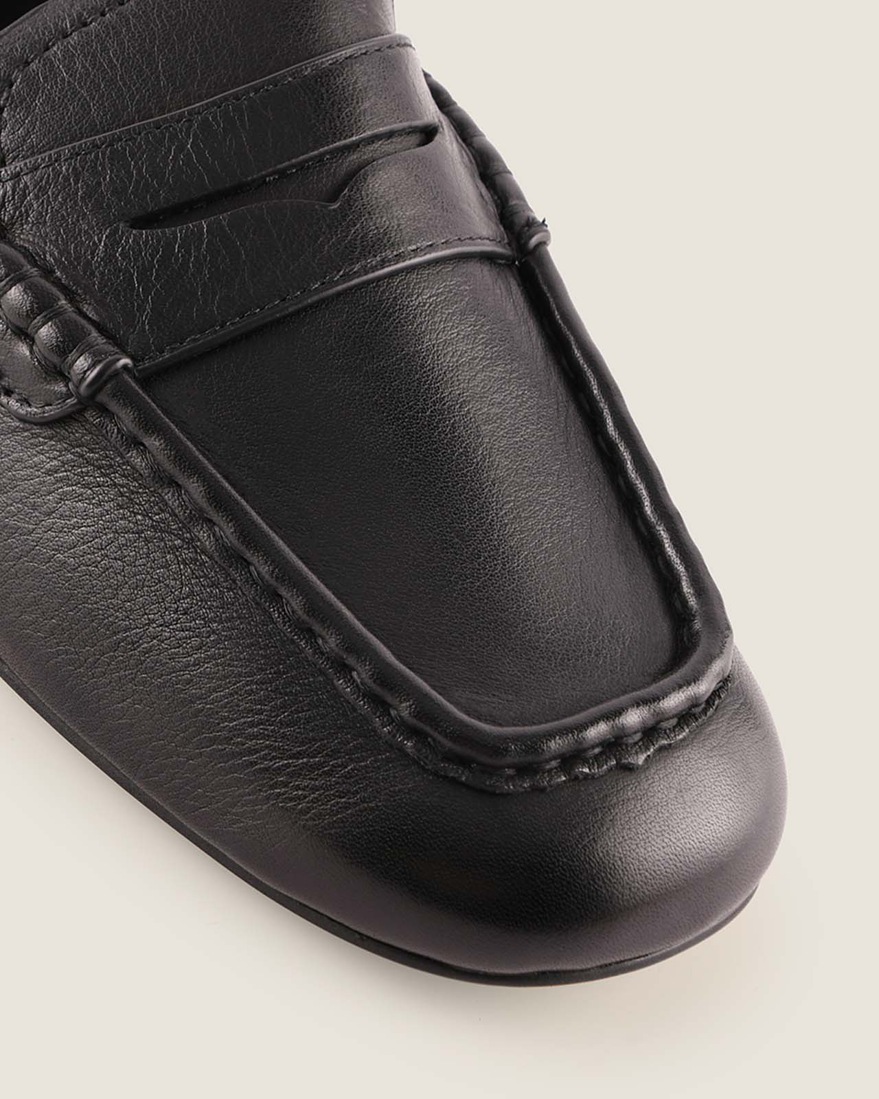 Close-up of a black leather loafer shoe on a light background
