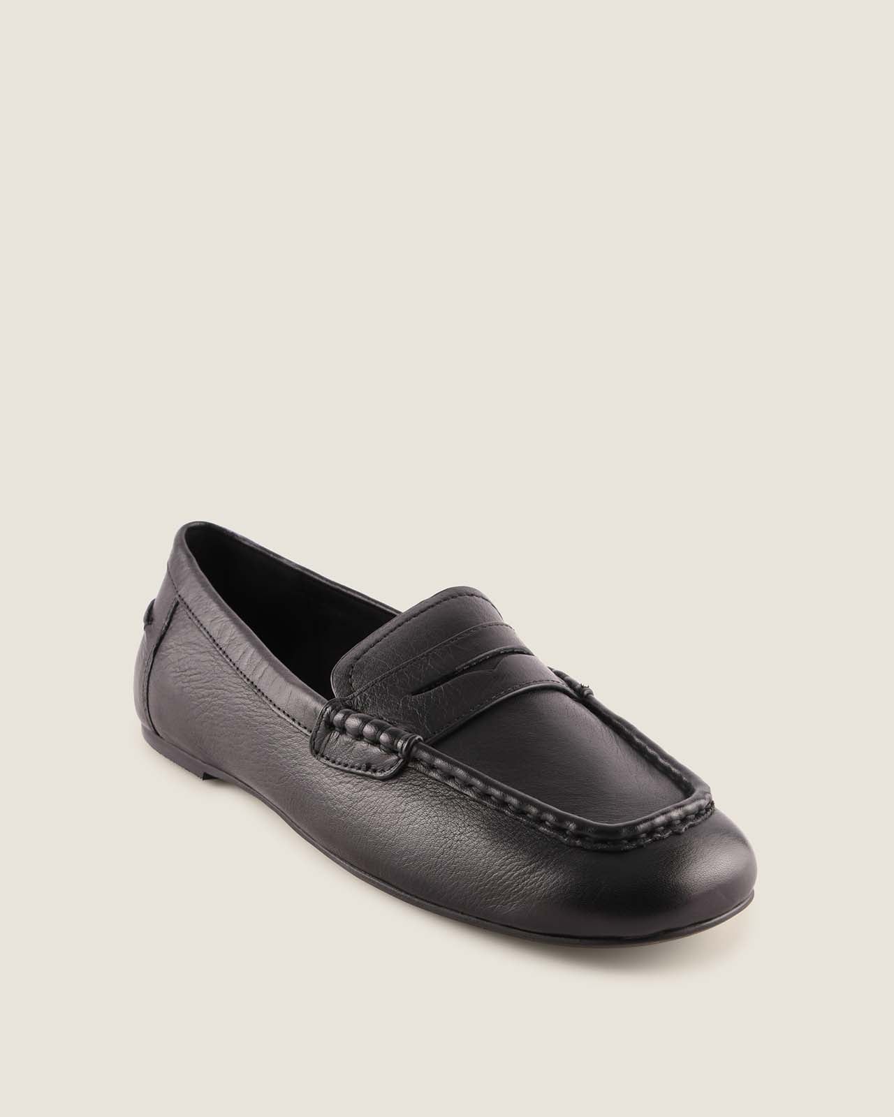 Black loafer shoe on a beige background