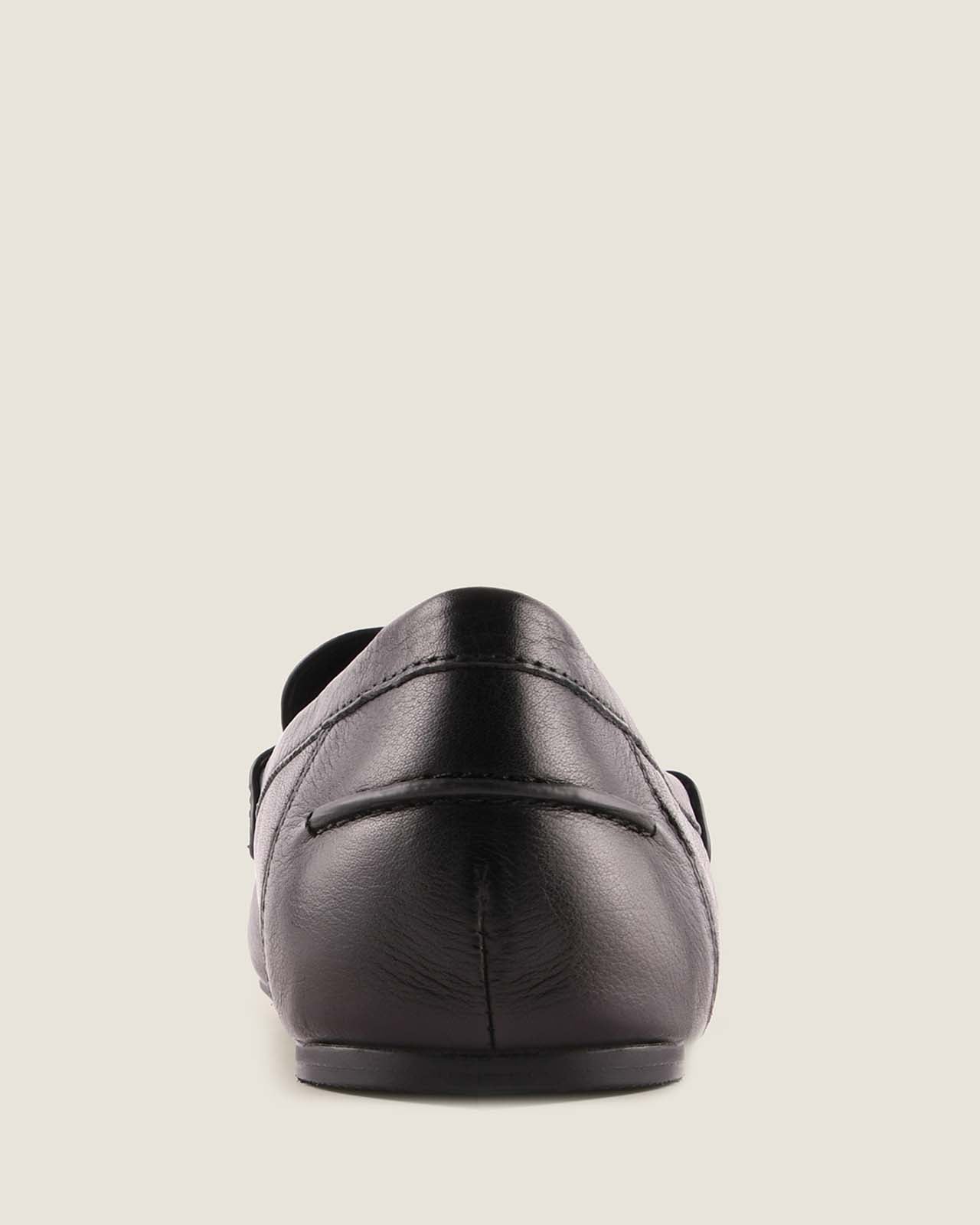 Black leather loafer shoe on a light grey background