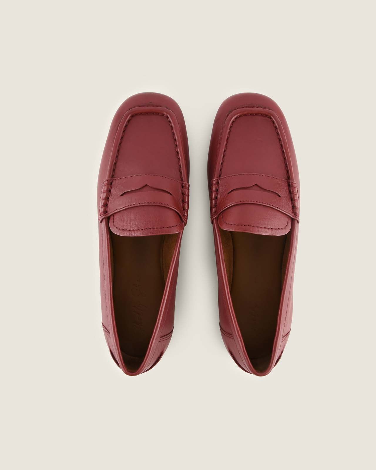 Pair of burgundy loafers on a light beige background