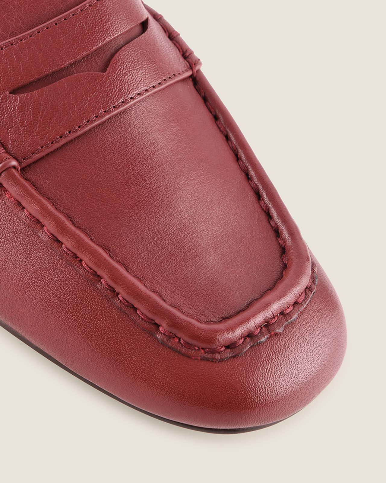 Burgundy leather loafer shoe on a beige background