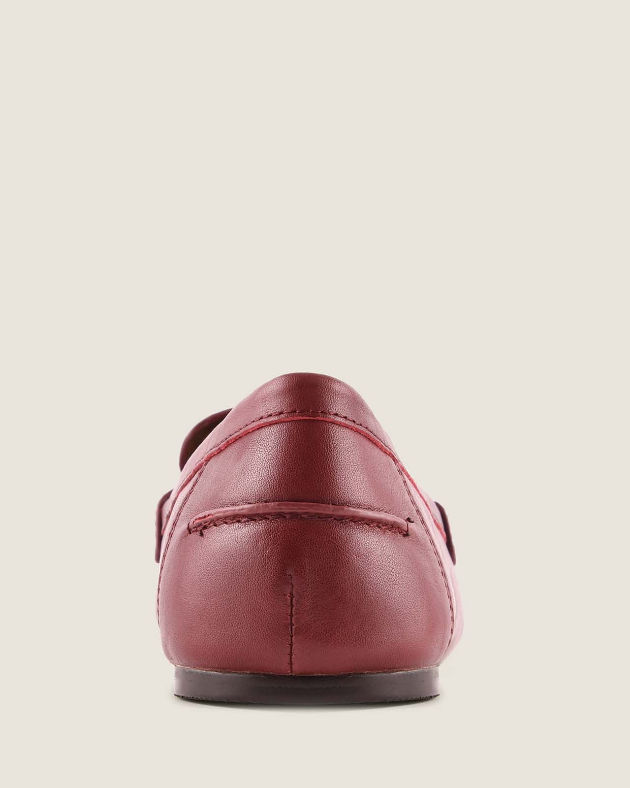 Burgundy leather loafer shoe on a beige background