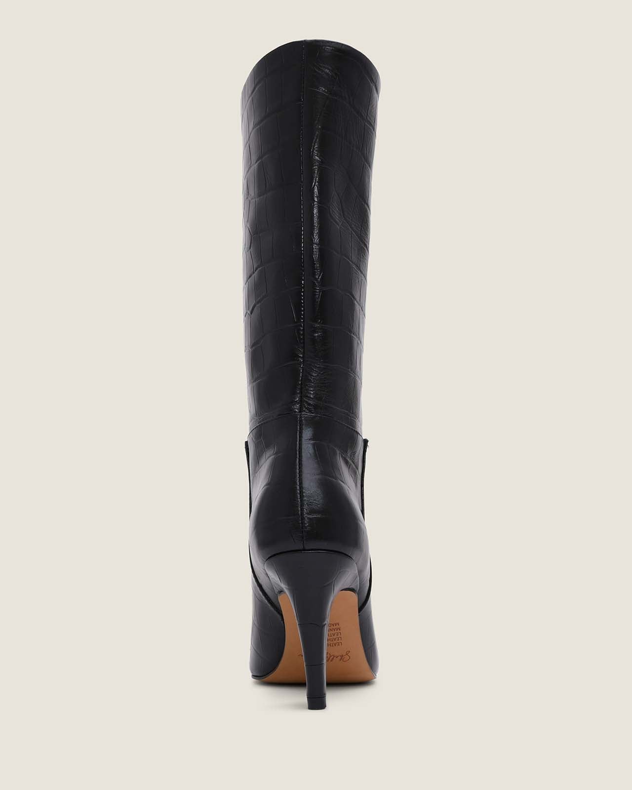 Black knee-high boot on a beige background