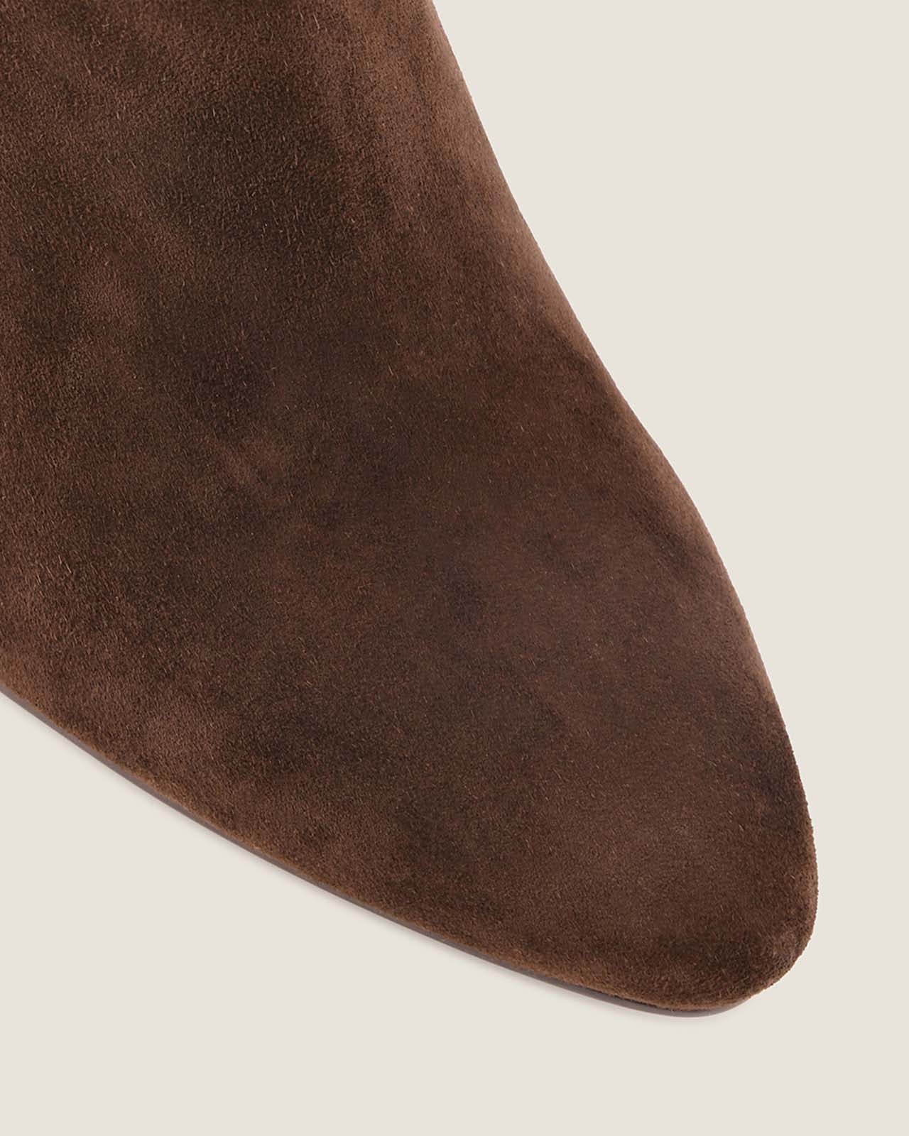Close-up of a brown suede shoe on a light grey background