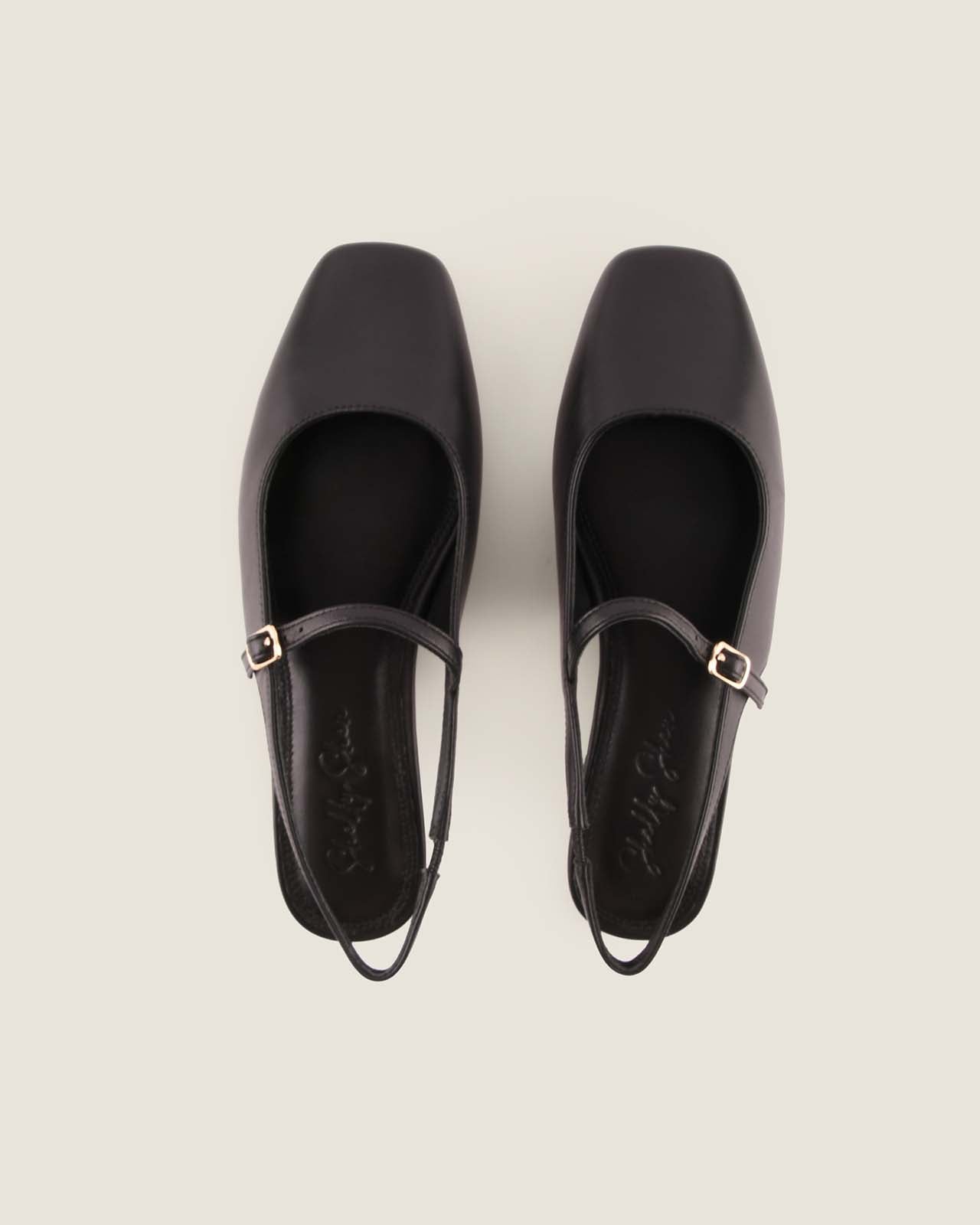 Pair of black shoes with a strap on a light grey background