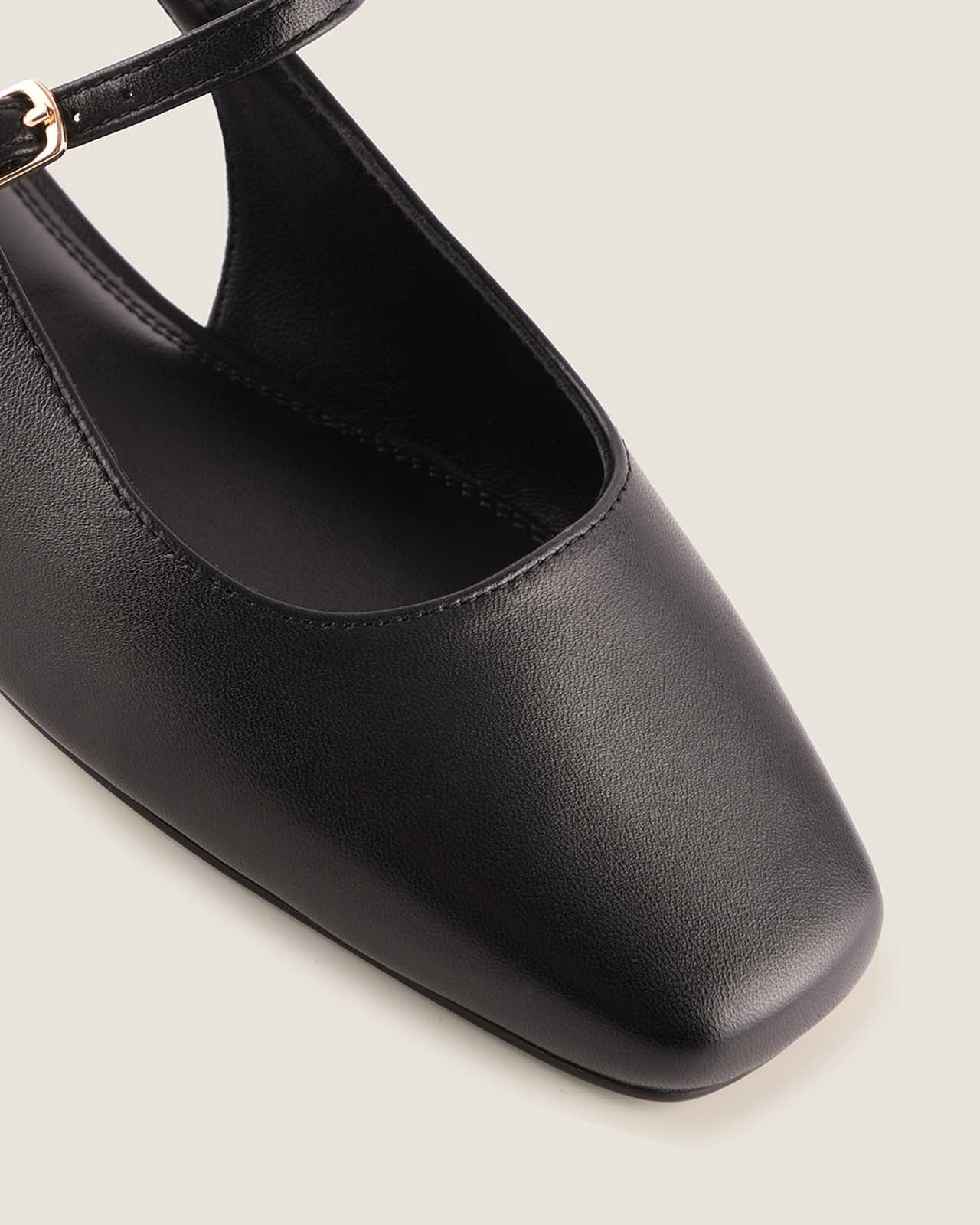 Black flat shoe with a square toe on a light grey background