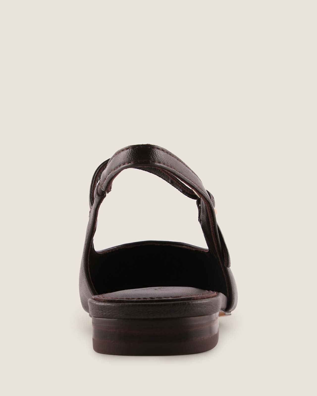 Brown leather dress flat shoe with a slingback strap on a beige background