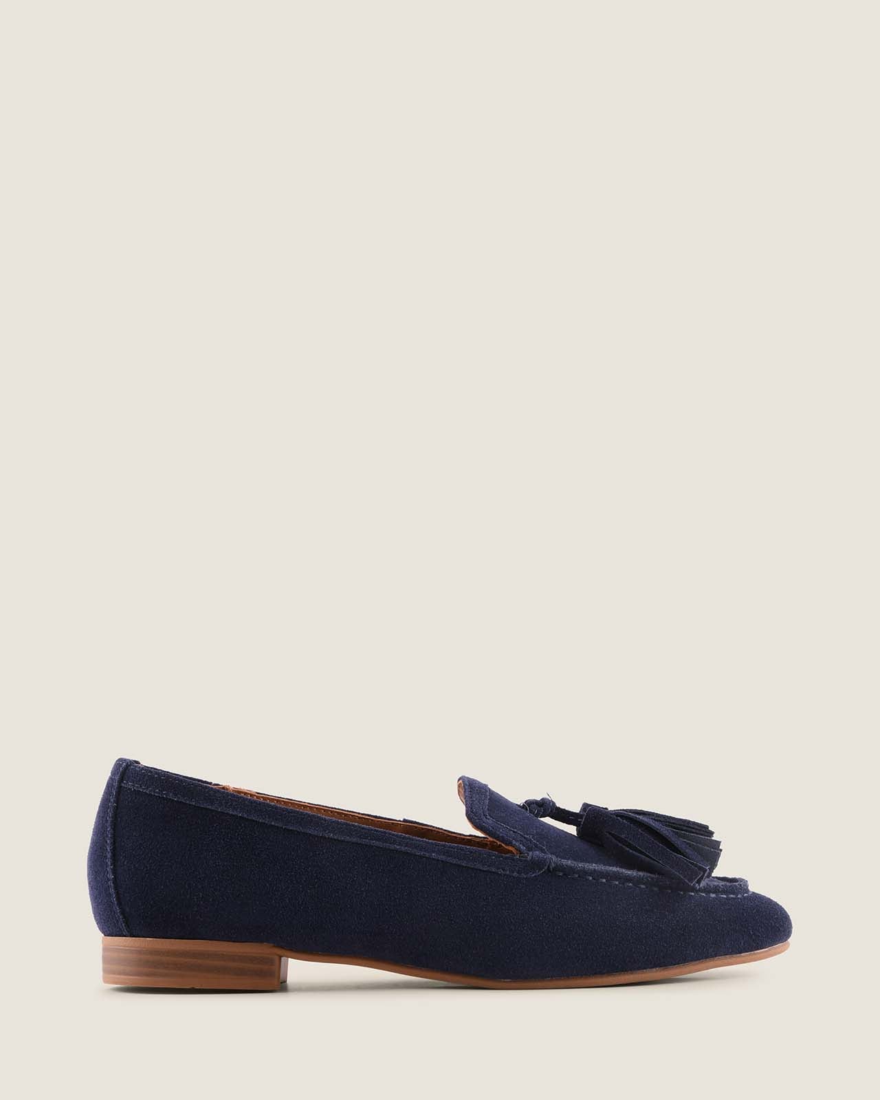 Navy blue suede loafer with a brown sole on a light beige background