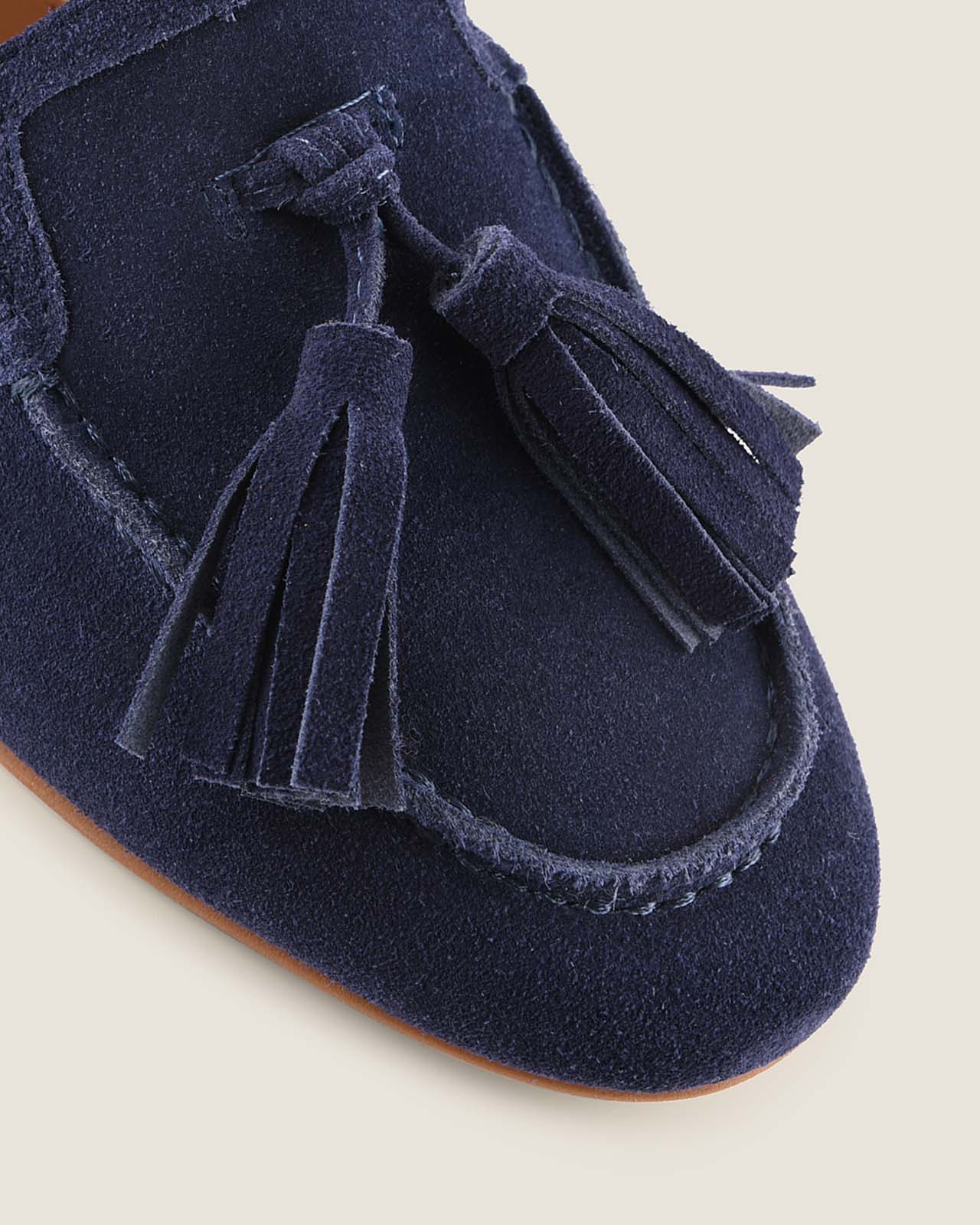 Navy blue suede moccasin shoe with tassels on a light background