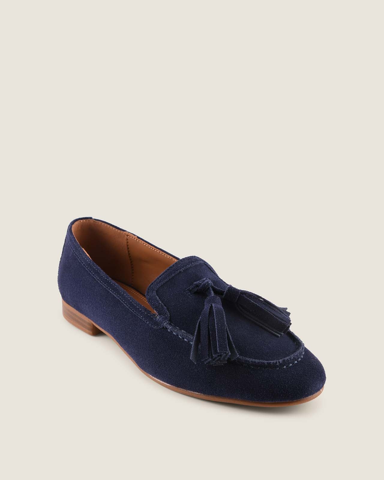 Navy blue loafer with tassels on a light beige background