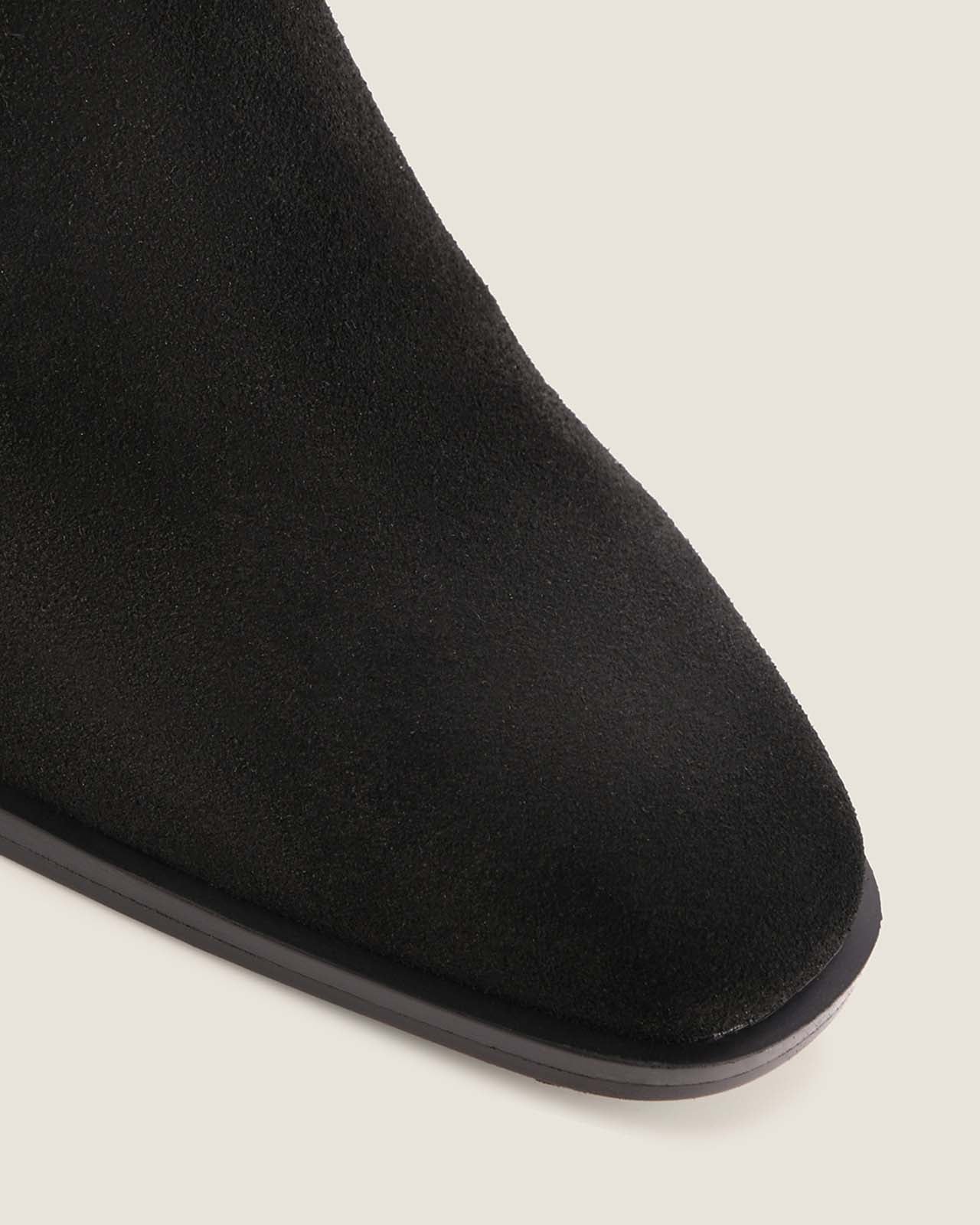 Black suede boot on a light grey background