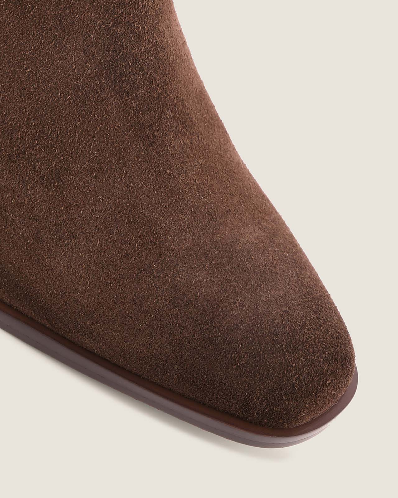 Brown suede boot on a beige background