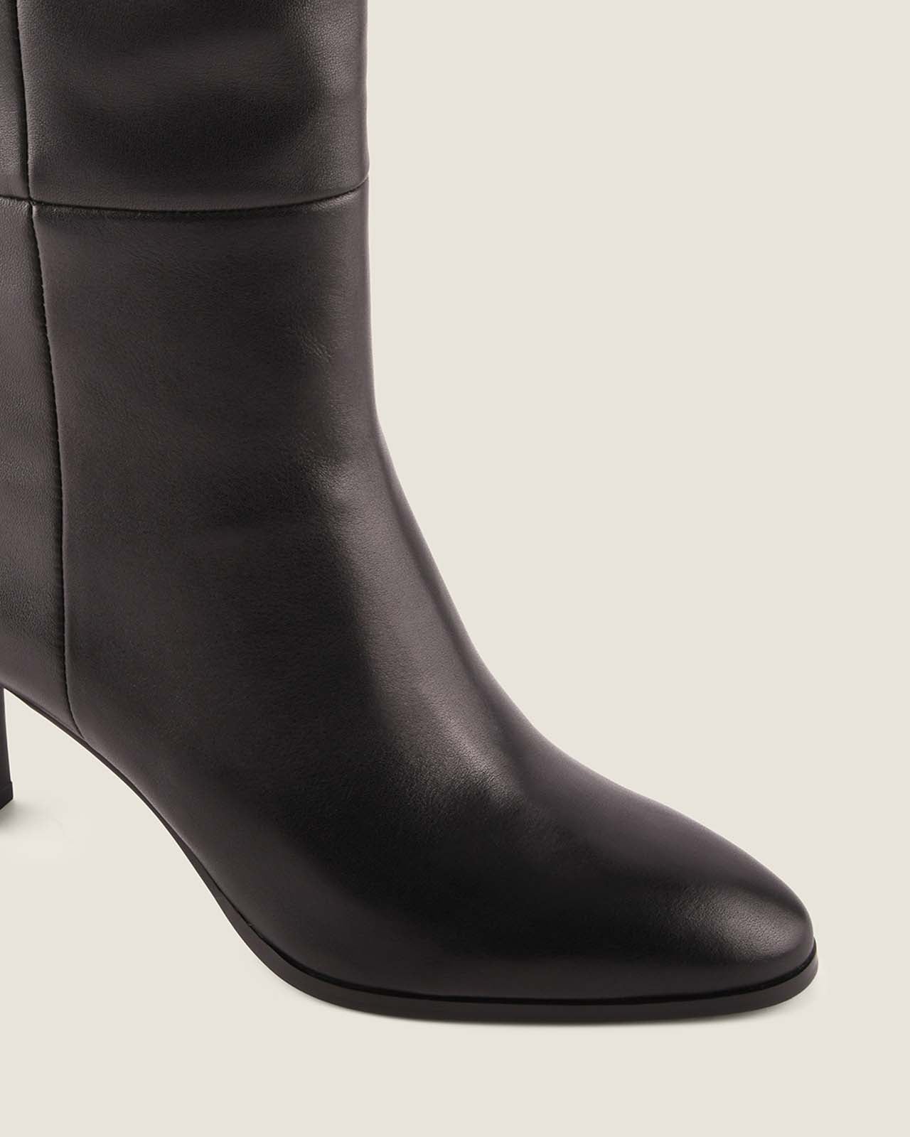 Black knee-high boot on a light grey background