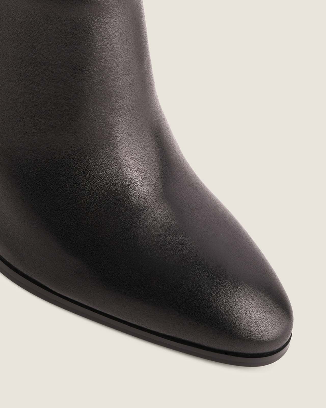 Black leather boot on a light grey background