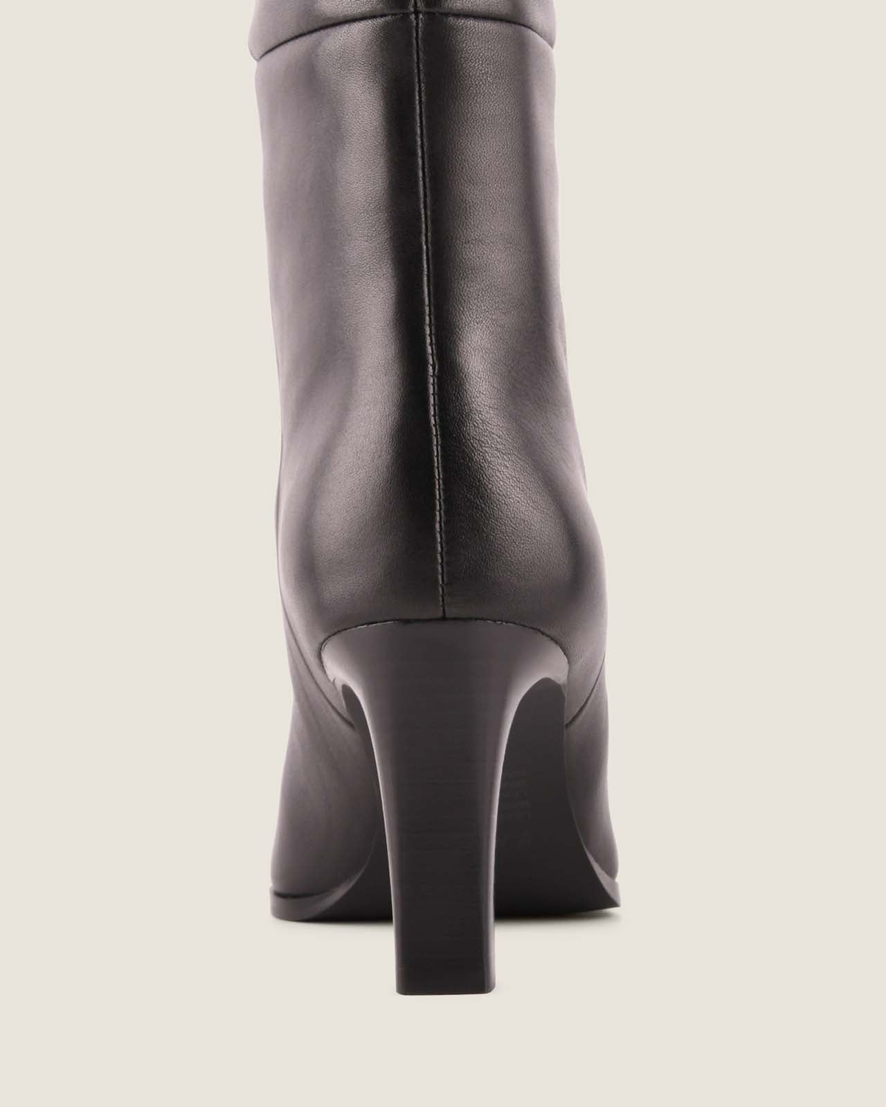Black leather knee-high boot with a block heel on a light grey background