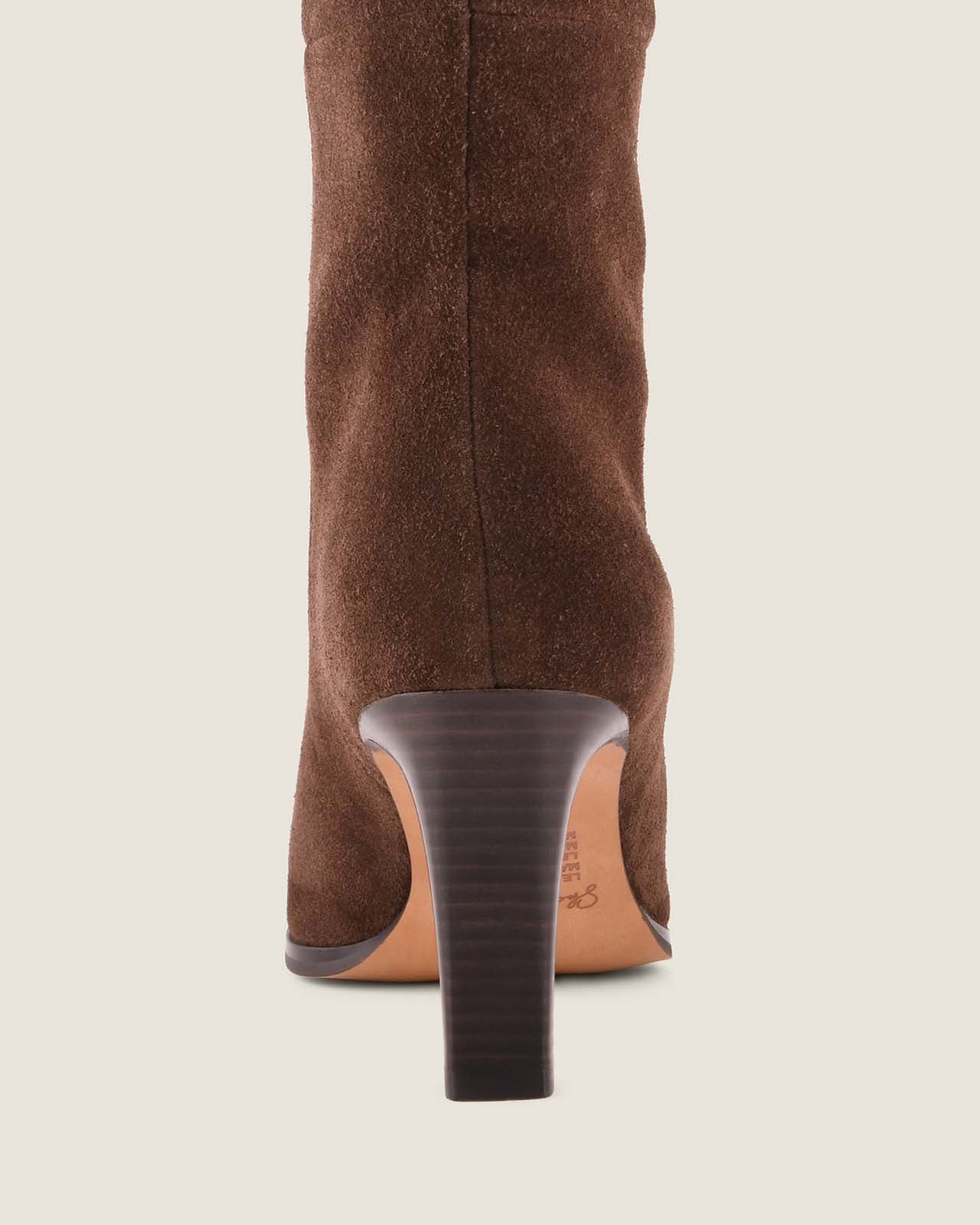 Brown knee-high boot with a block heel on a light beige background