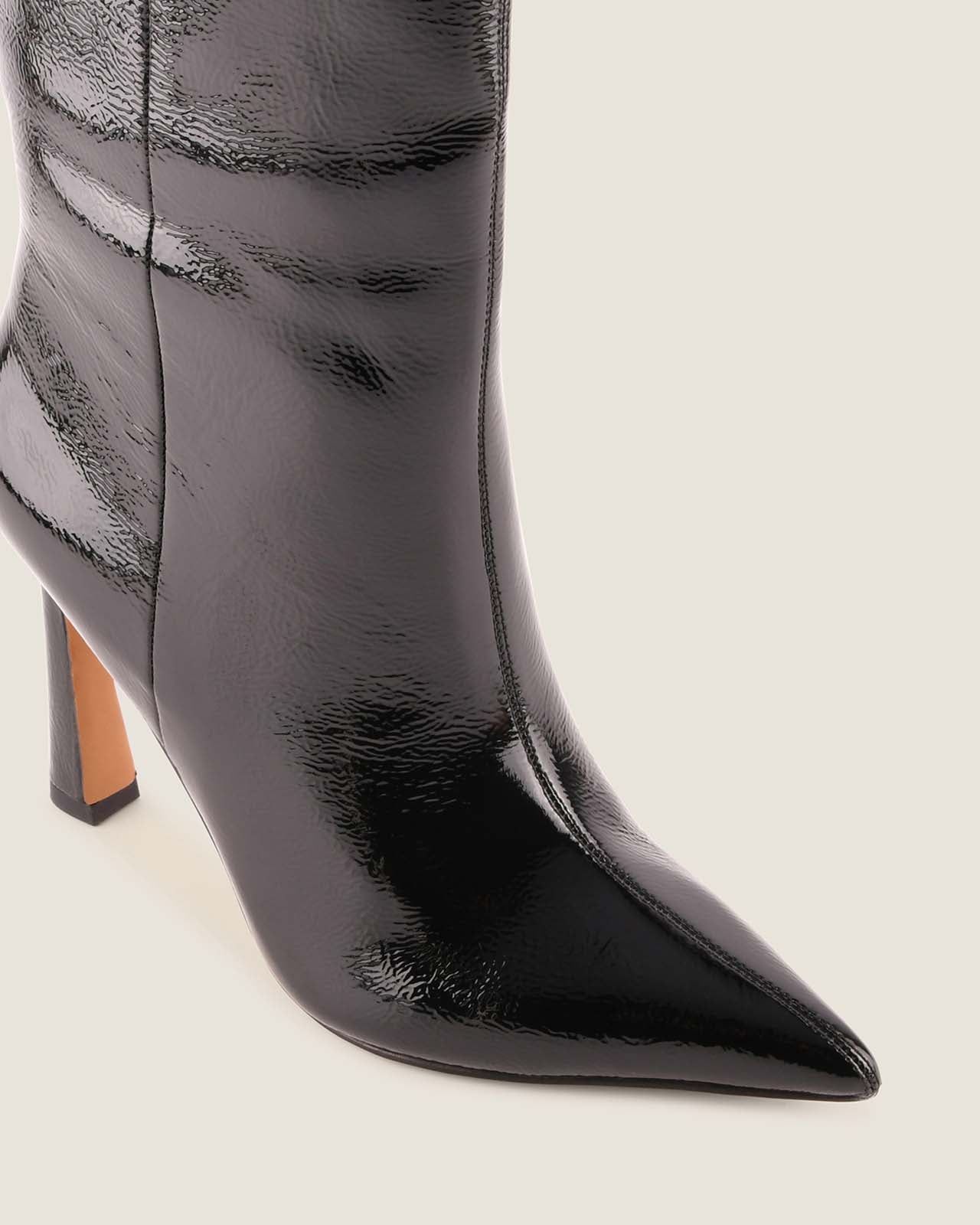Black patent leather pointed-toe boot on a light gray background