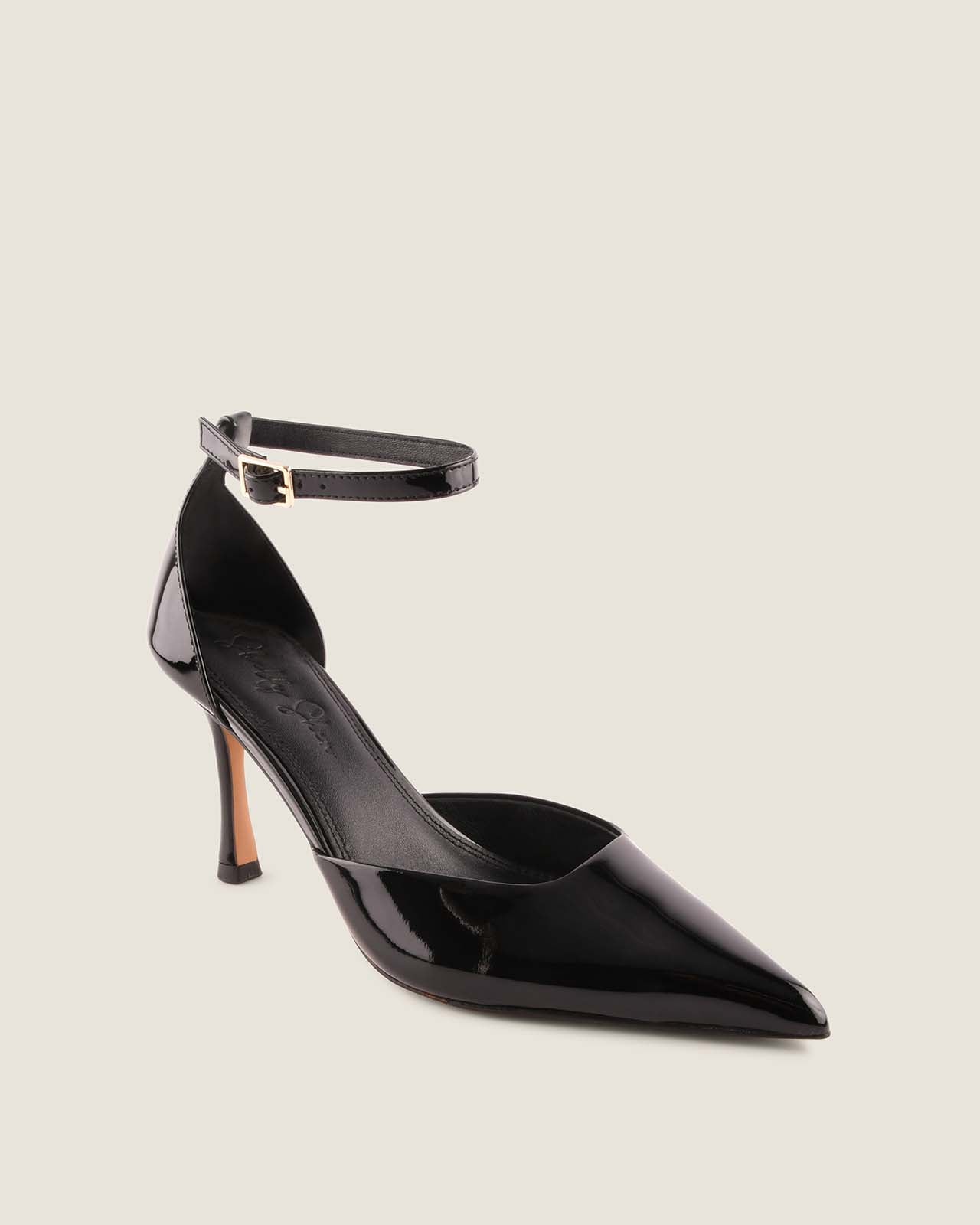 Black high-heeled shoe with ankle strap on a light gray background