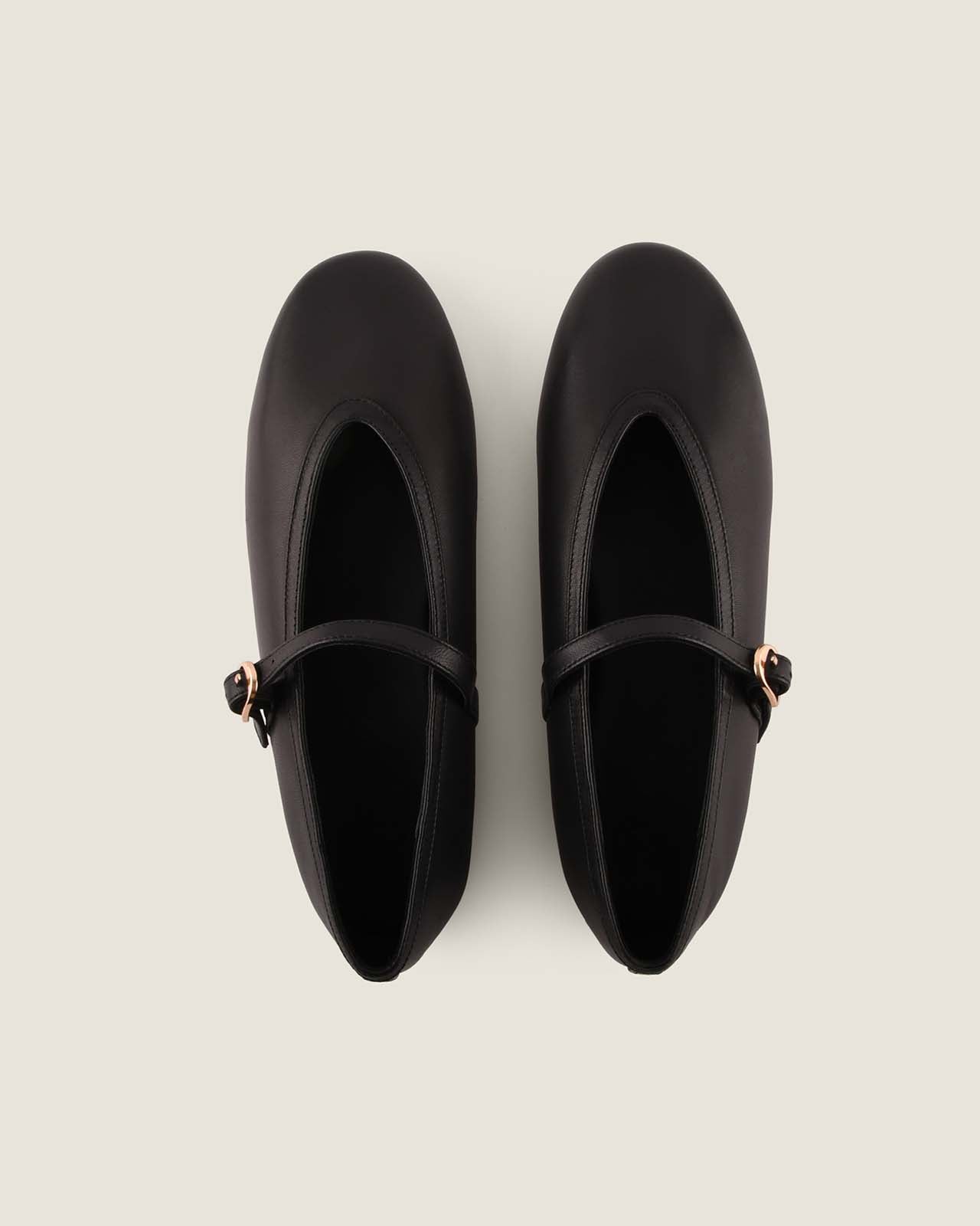 Pair of black shoes with a strap on a light gray background
