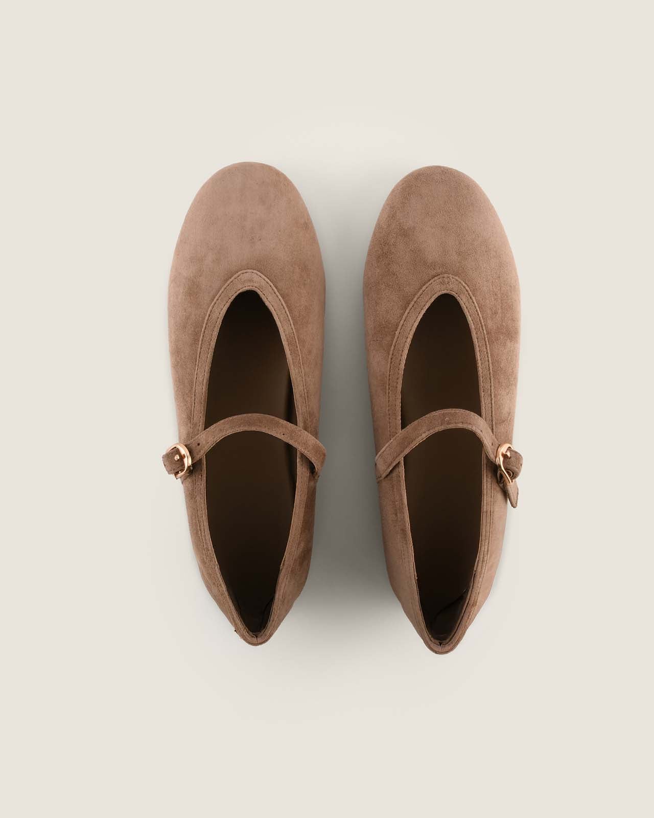 Pair of brown suede shoes with a strap on a light gray background