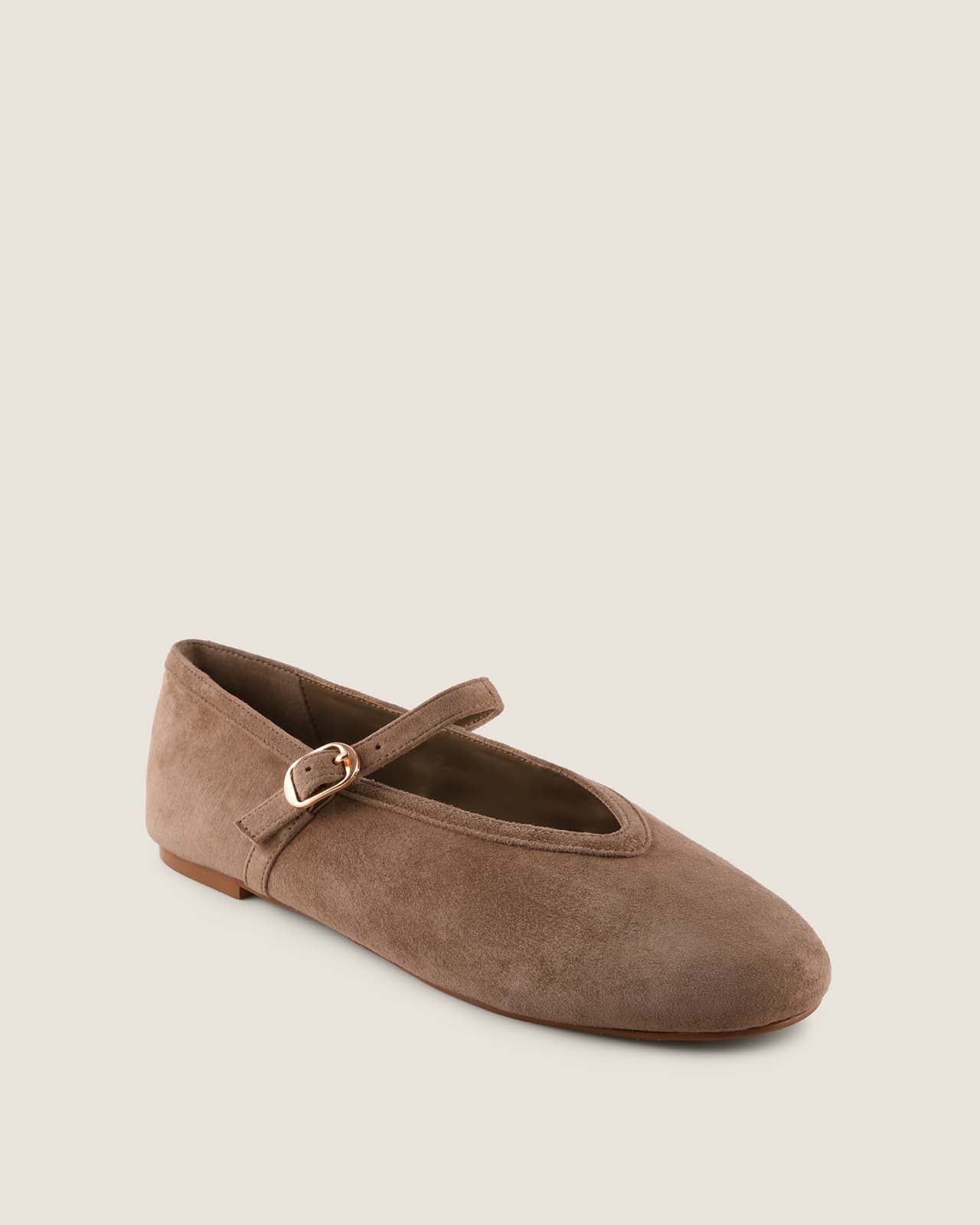 Brown suede flat shoe with a strap on a beige background