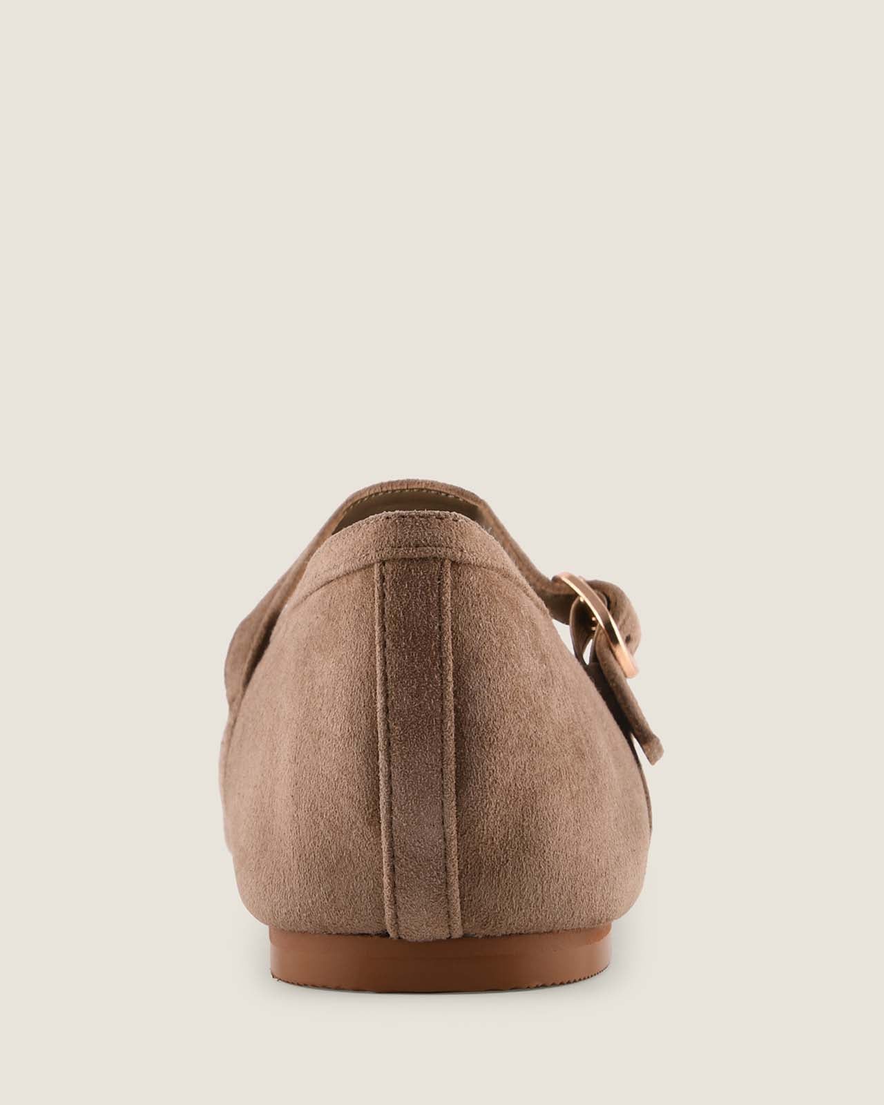 Brown suede shoe with a strap on a light beige background