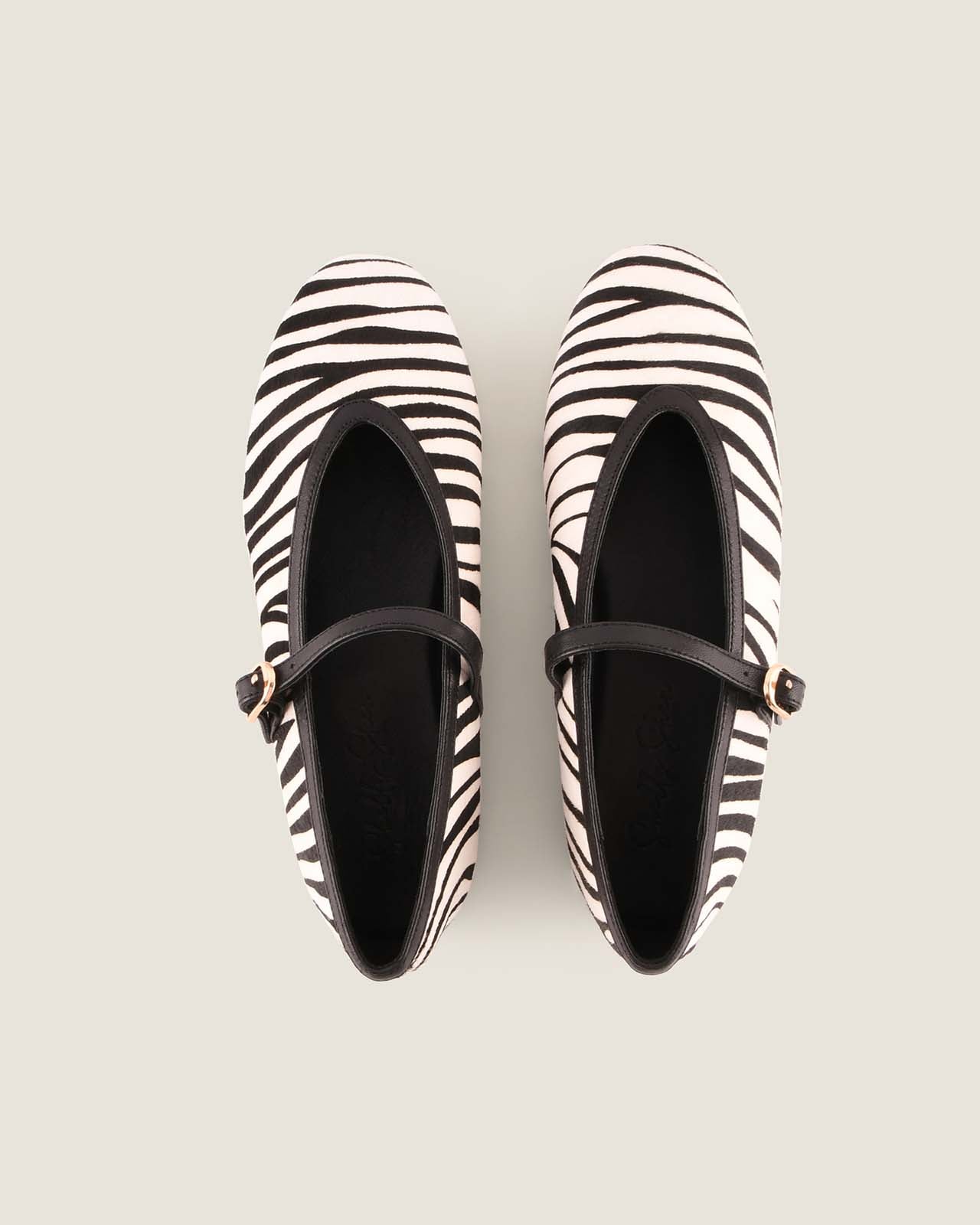 Pair of zebra-striped flats on a light gray background