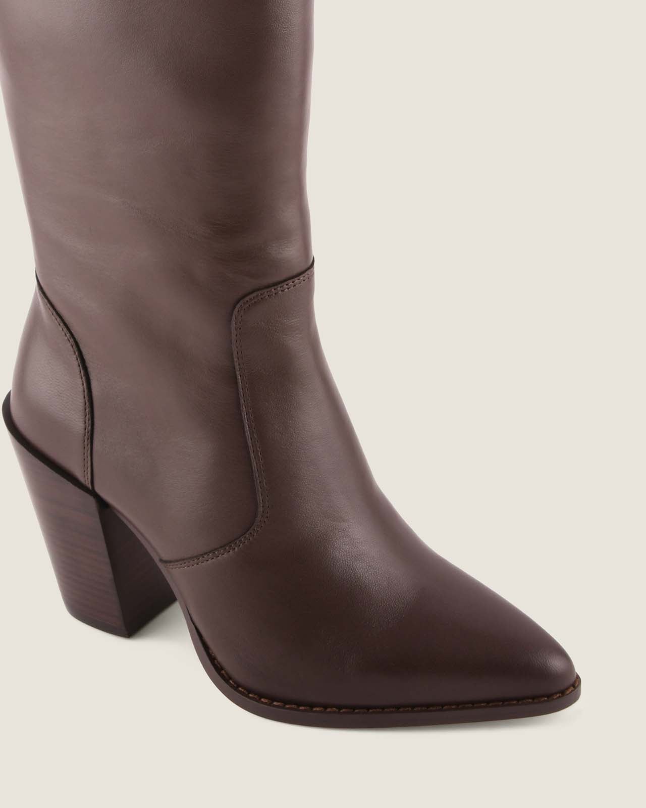 Brown knee-high boot with a block heel on a light beige background