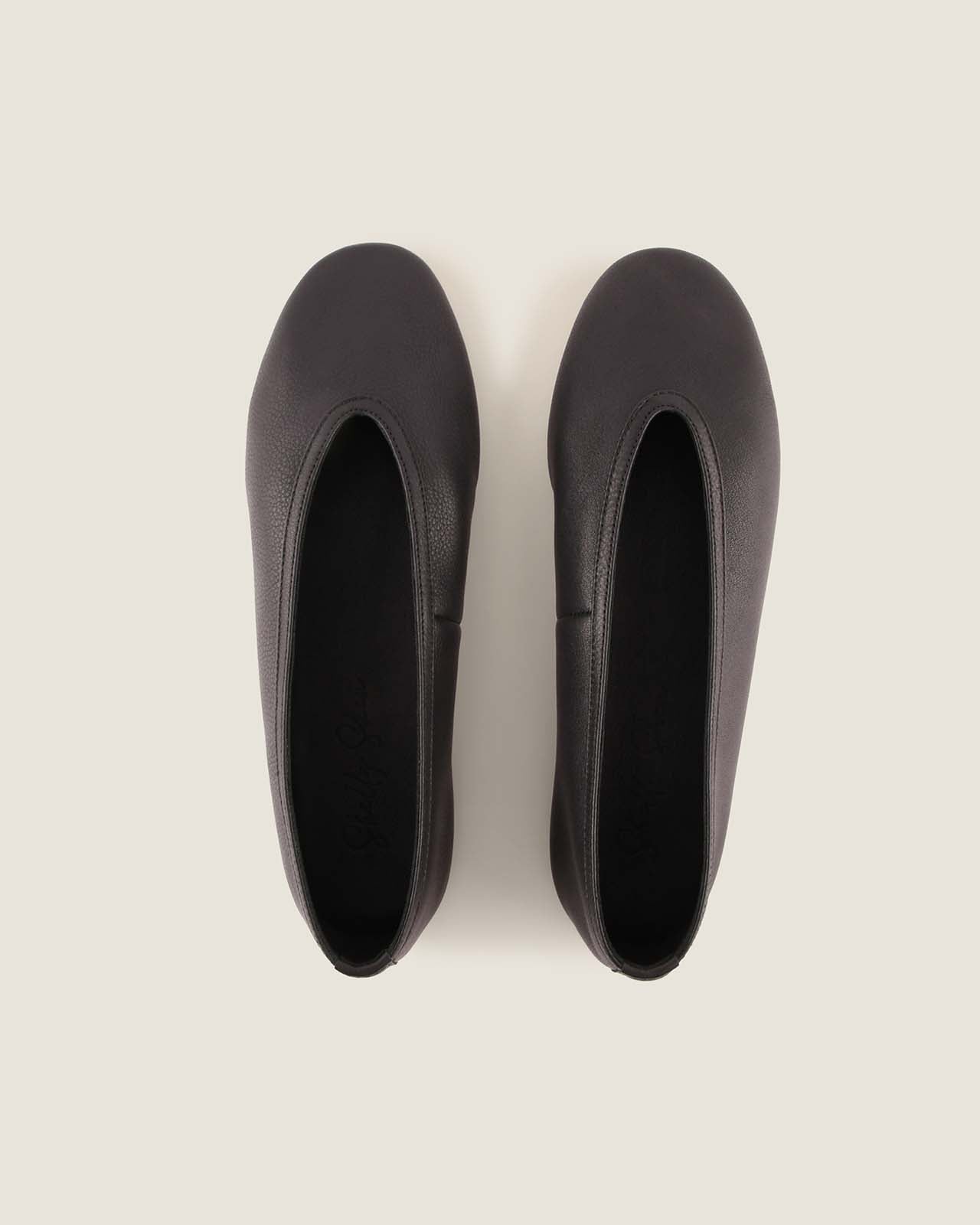 Pair of black ballet flats on a light gray background