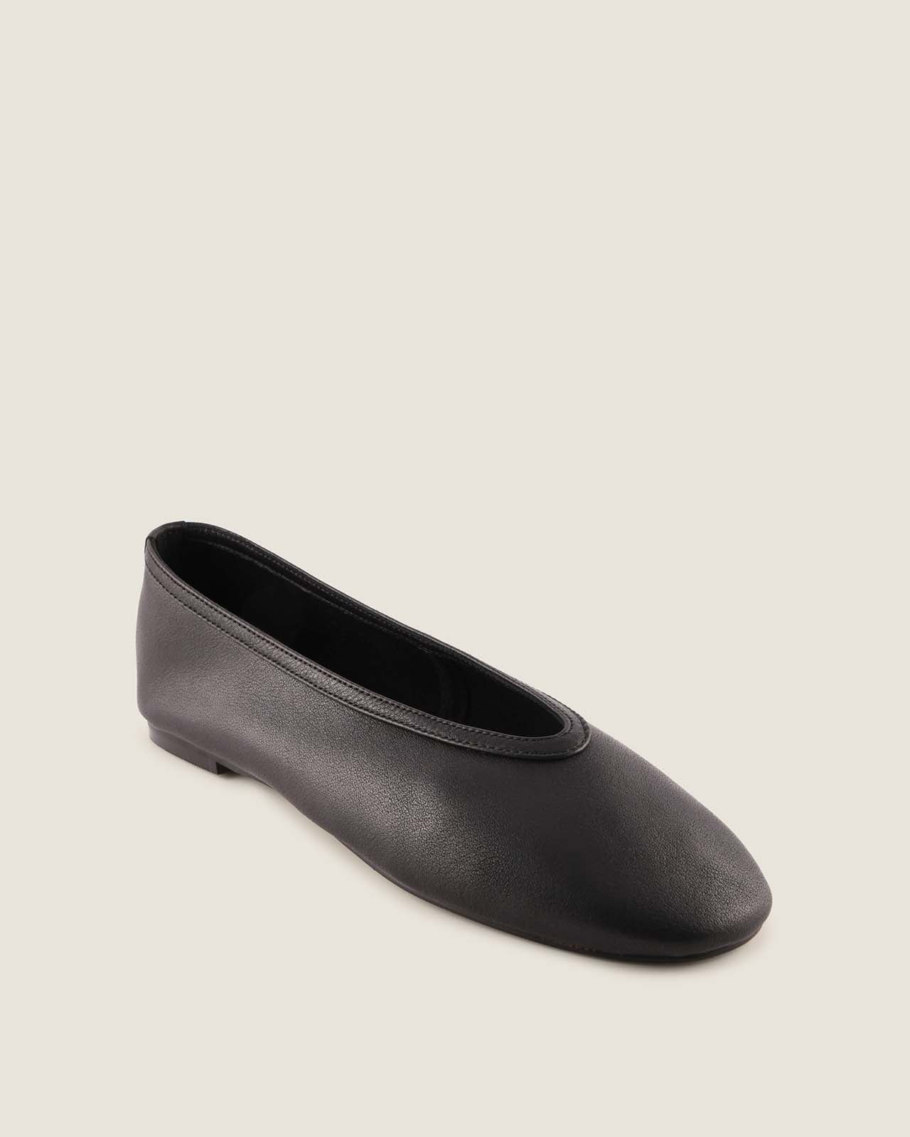 Black flat shoe on a beige background