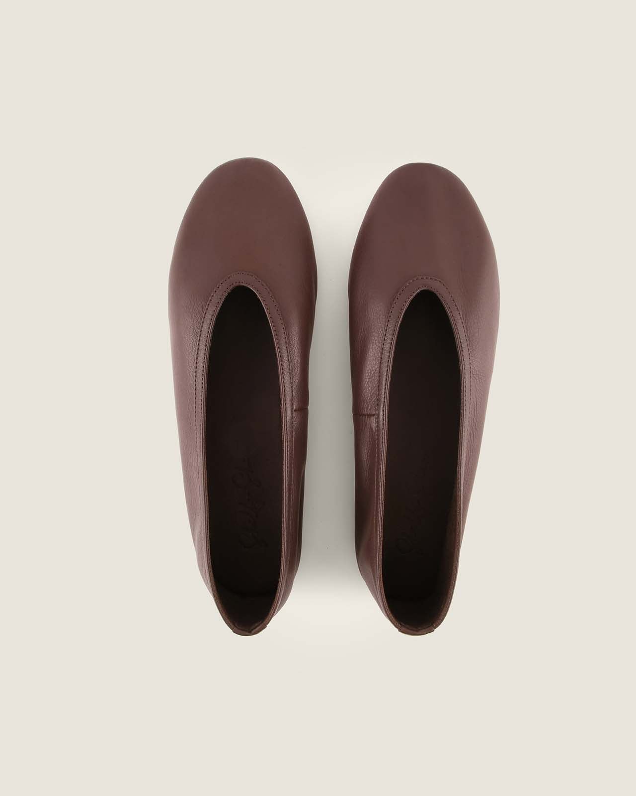 Pair of brown flat shoes on a light beige background