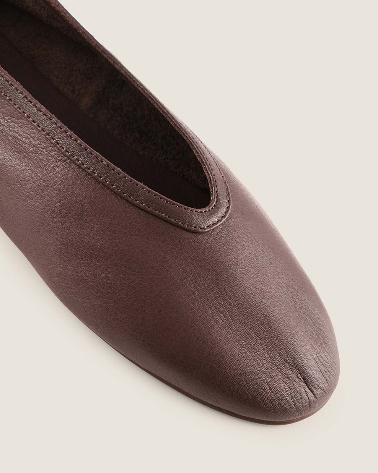Brown leather flat shoe on a light gray background