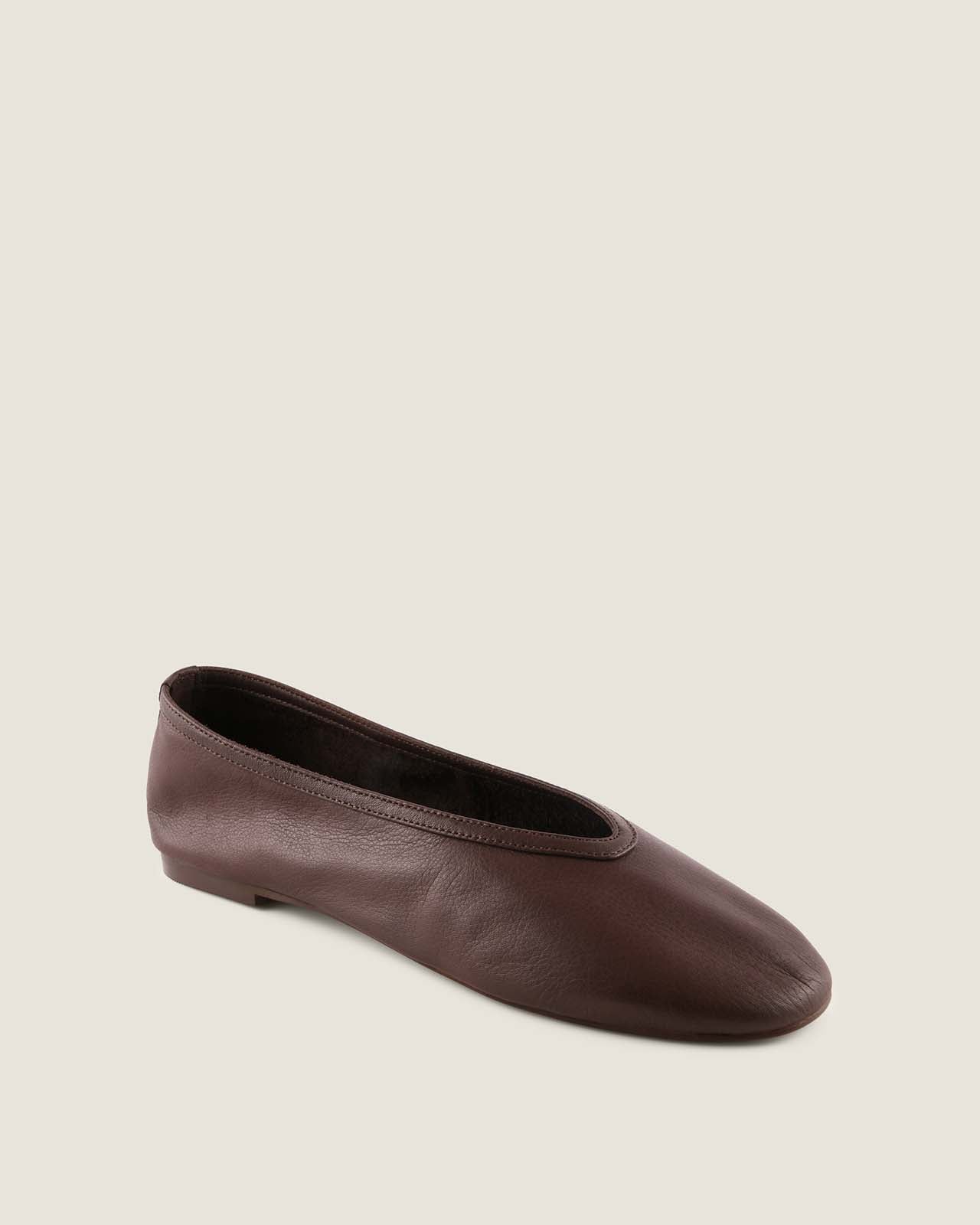 Brown leather flat shoe on a beige background