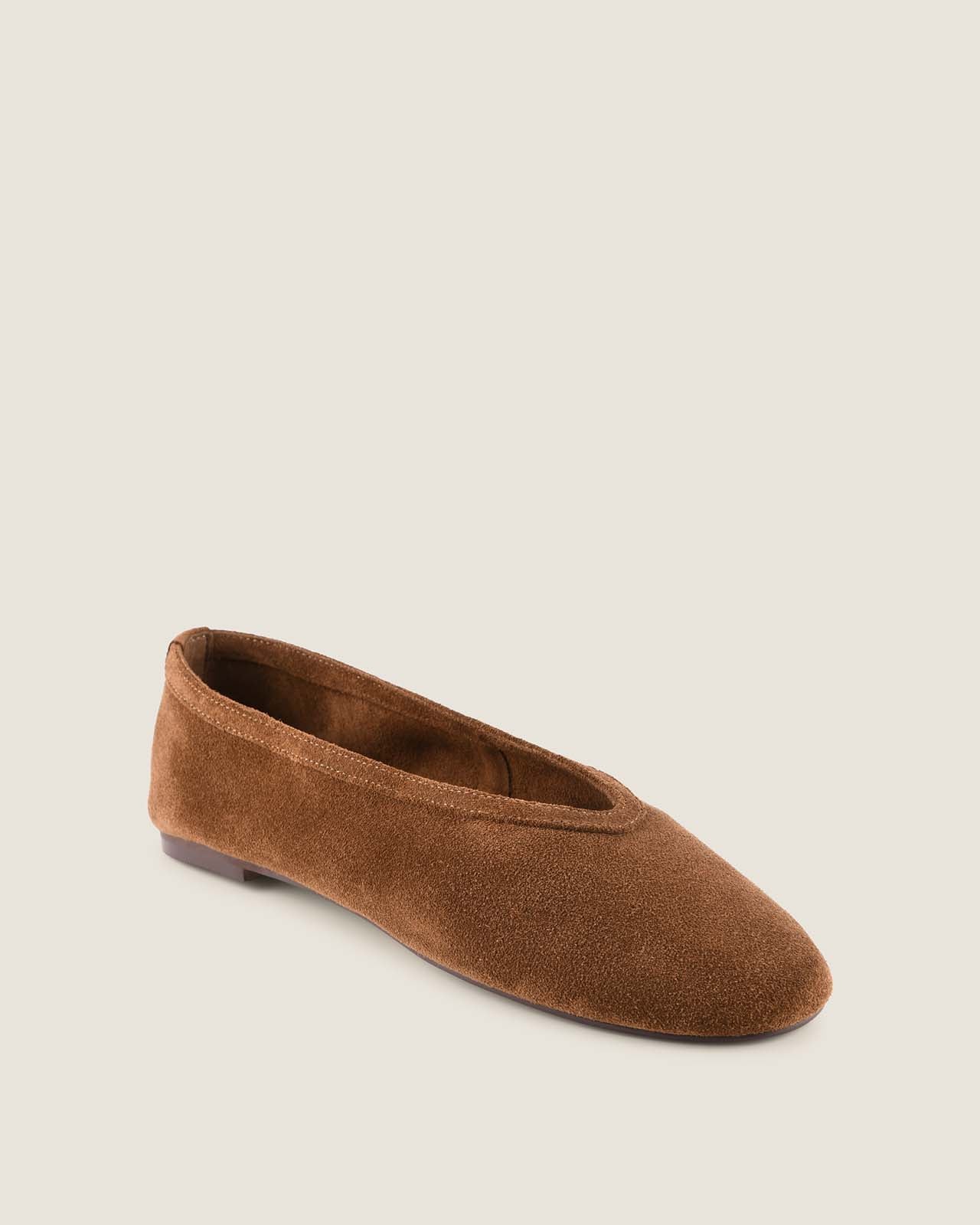 Brown suede flat shoe on a light beige background