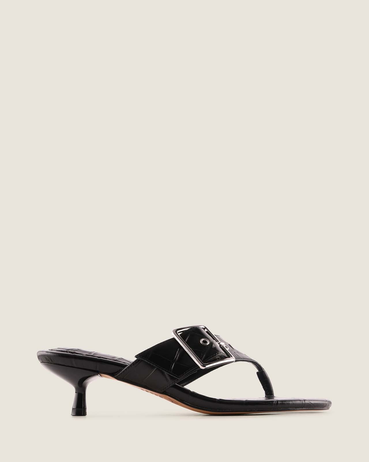 Black sandal with a strap on a light beige background