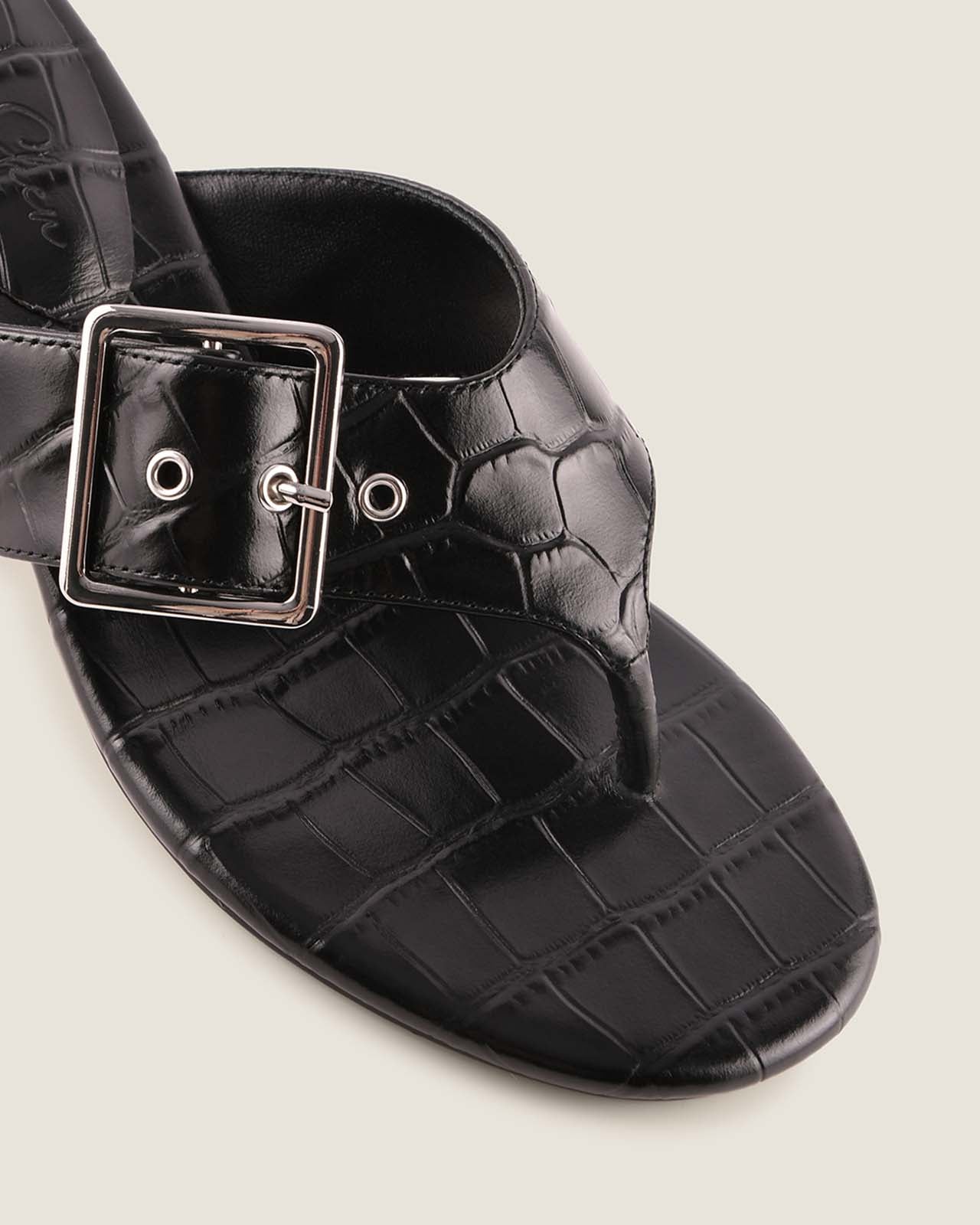 Black crocodile-patterned sandal with a silver buckle on a light gray background