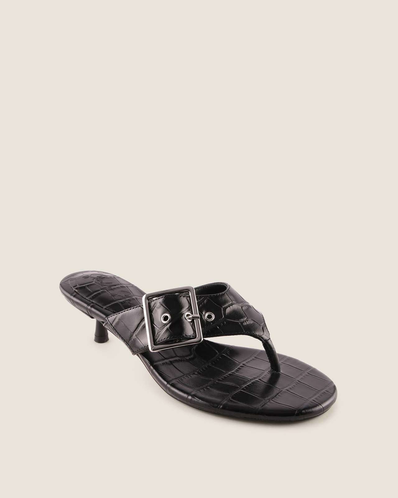 Black sandal with a buckle on a beige background