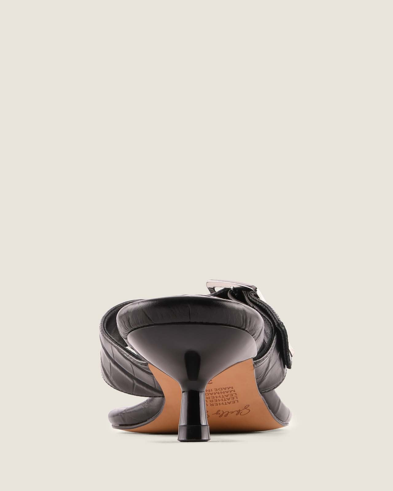 Black high-heeled shoe with a strap on a light gray background