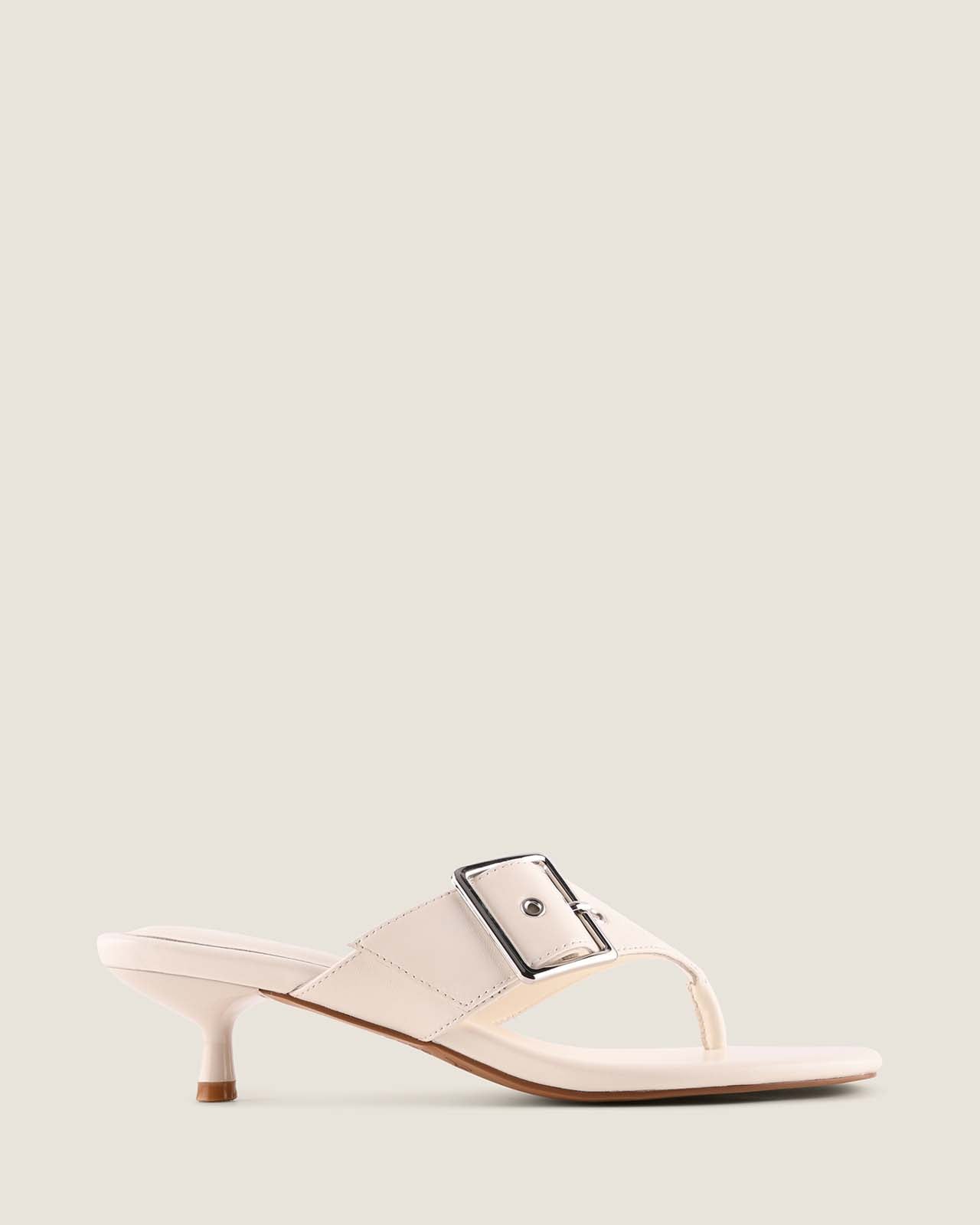 White sandal with a small black strap on a light gray background