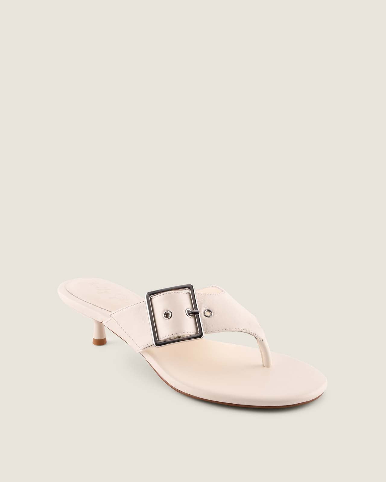 White sandal with a black buckle on a light gray background
