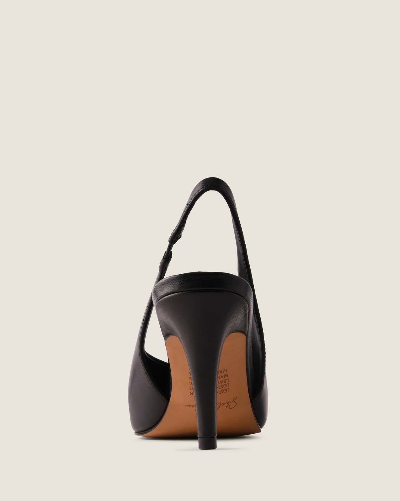 Black high-heeled shoe with a thin strap on a beige background